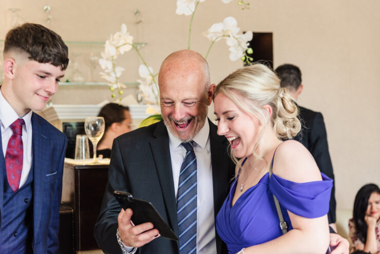 Smiling group looking at a phone together.