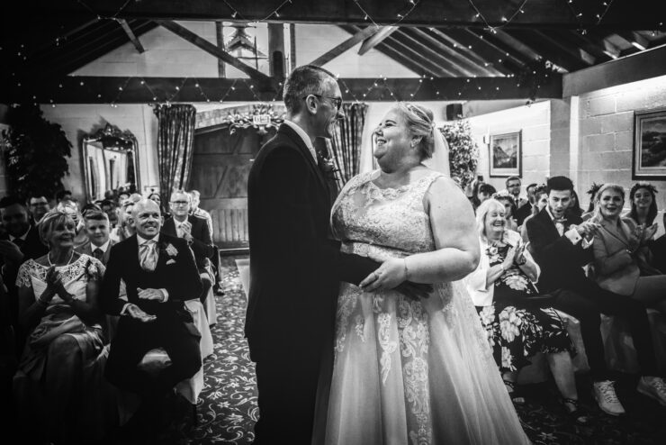 Happy couple dances at cosy indoor wedding ceremony.