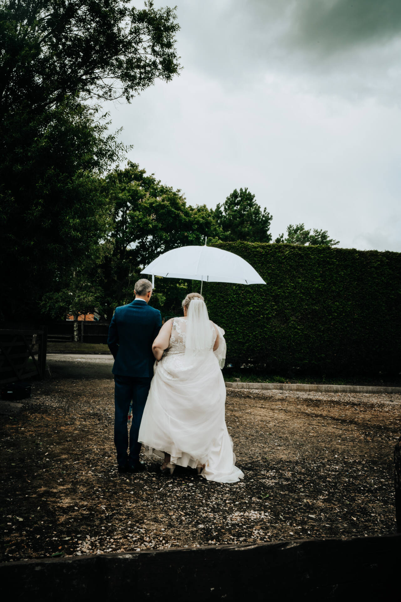 Bride and groom under umbrella on wedding day.