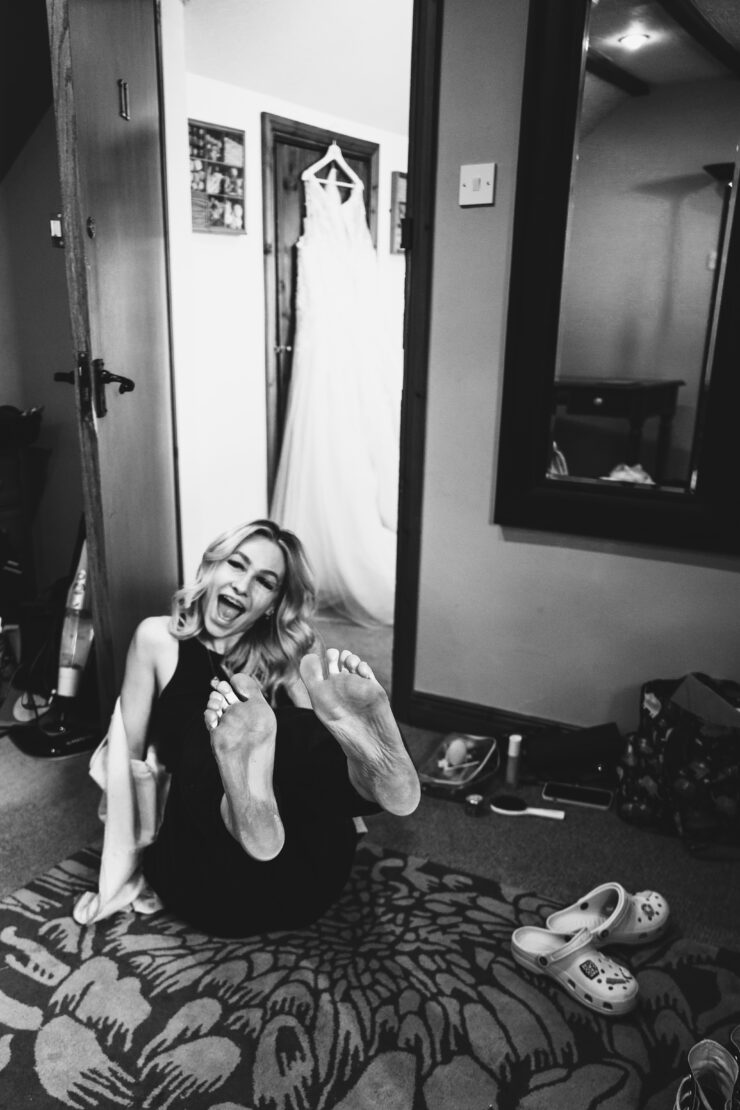 Laughing woman, feet up, wedding dress background.