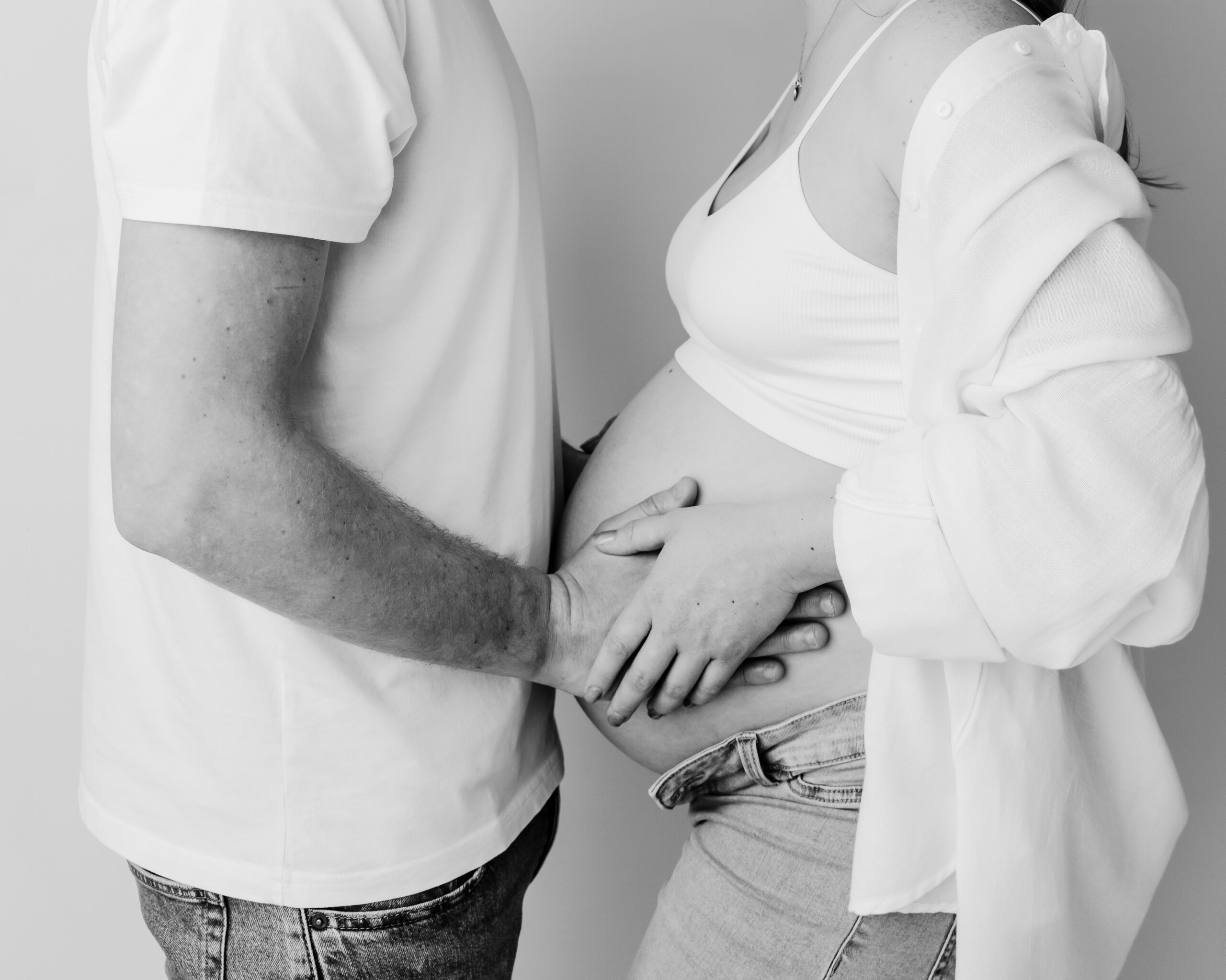 Couple gently touching pregnant belly, monochrome photo.