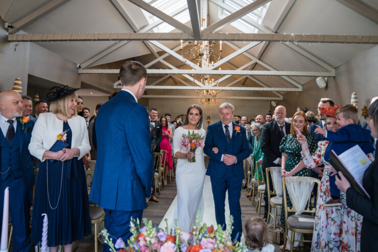 Bride walking down aisle at wedding ceremony.