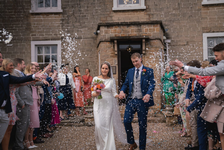 Bride and groom leaving wedding with confetti.