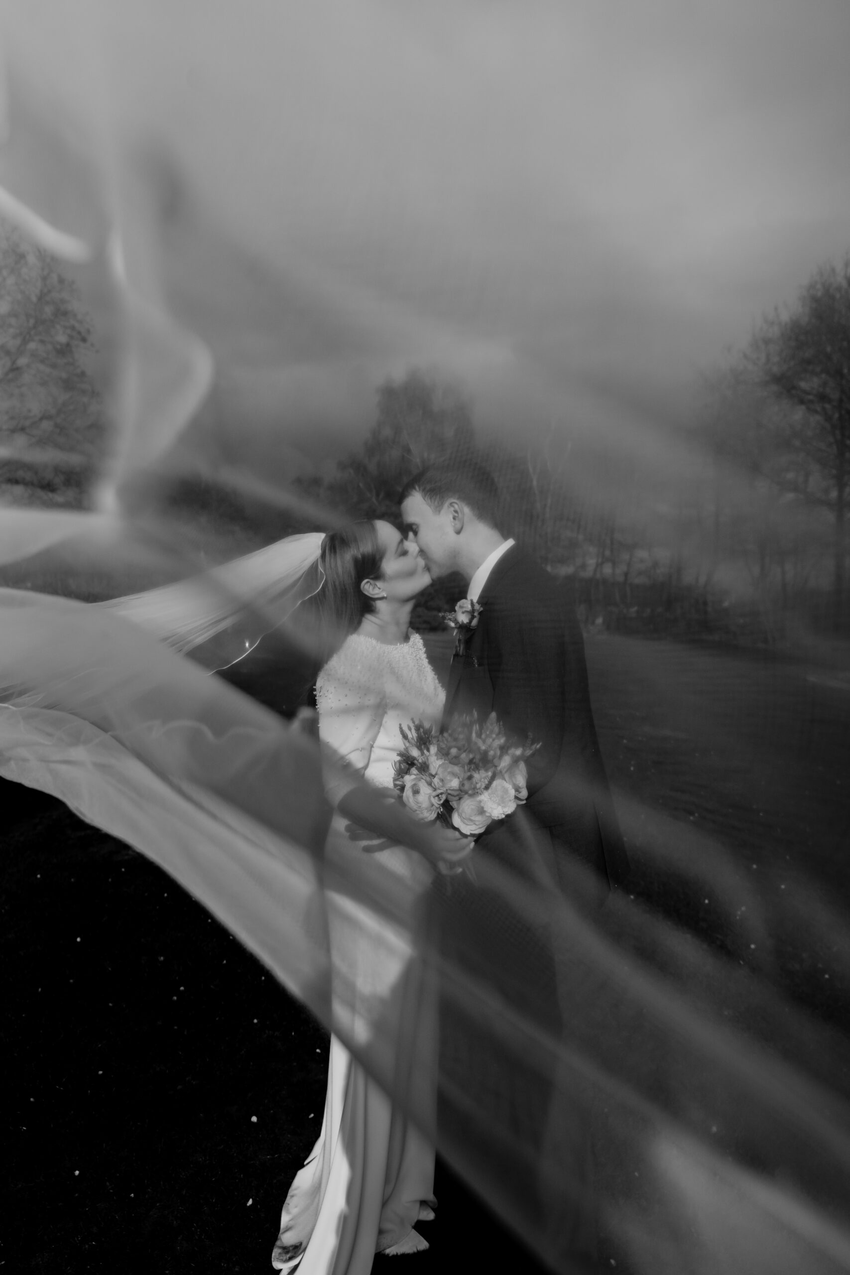 Romantic wedding couple kissing under veil