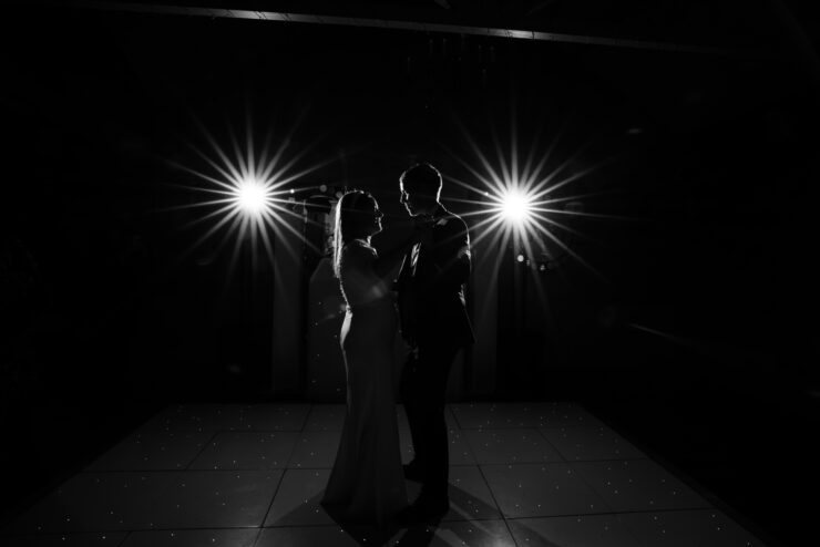 Silhouetted couple dancing under bright lights.