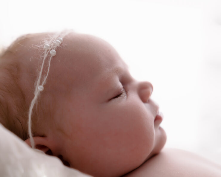 Sleeping baby with headband, side profile view.