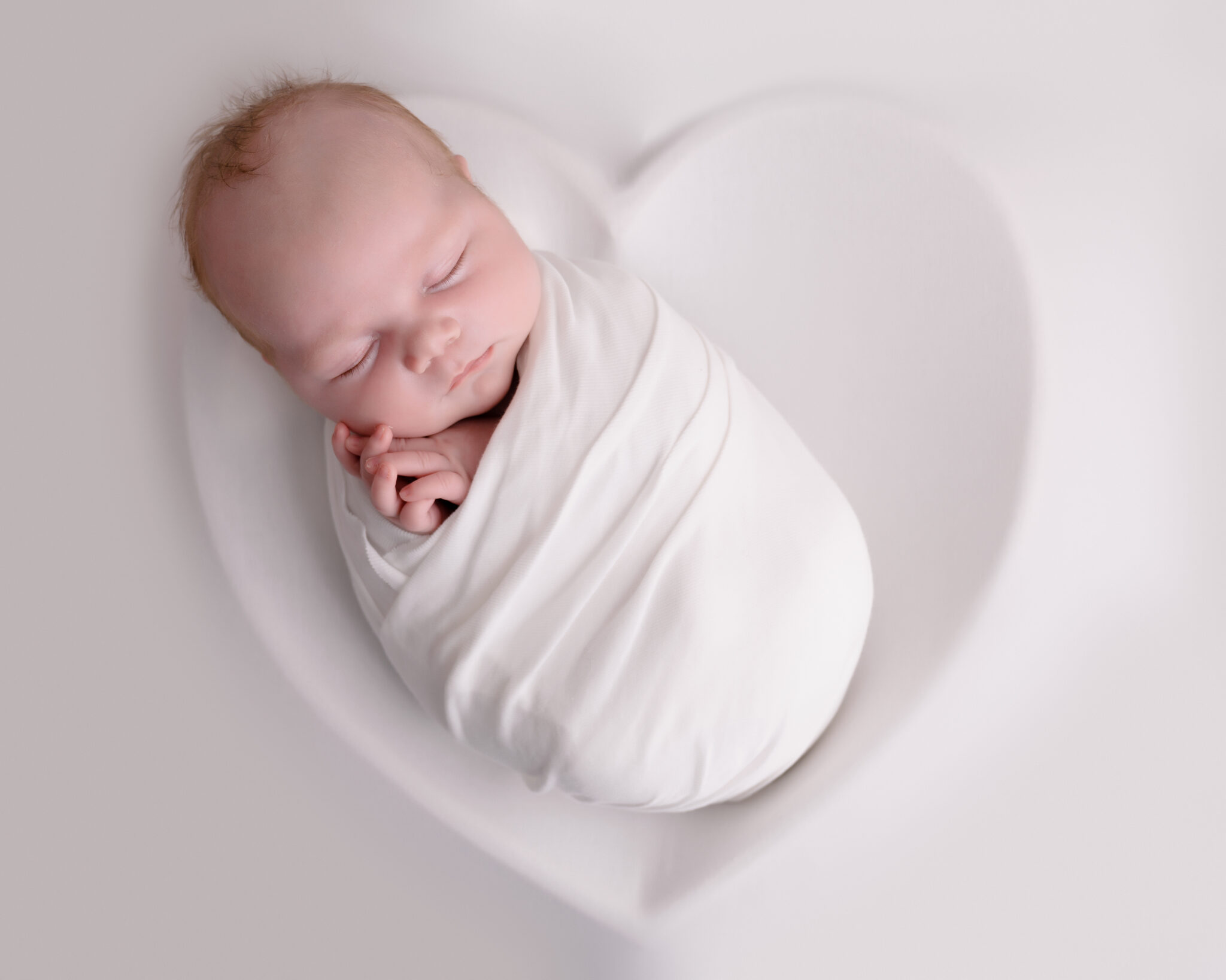 Sleeping newborn wrapped in white blanket