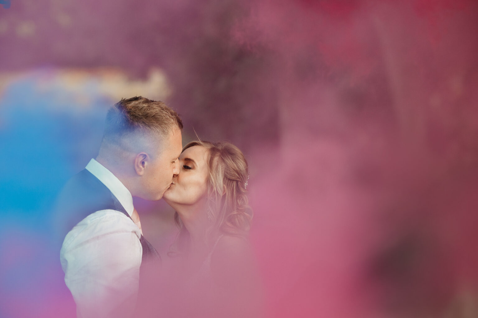Couple kissing surrounded by colourful smoke