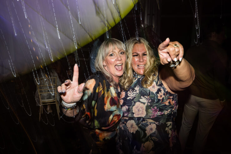 Two women dancing at a party, having fun.