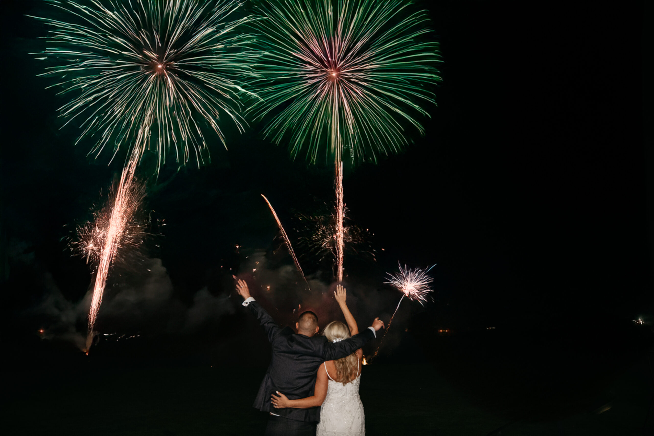 Couple celebrating under fireworks display at night.