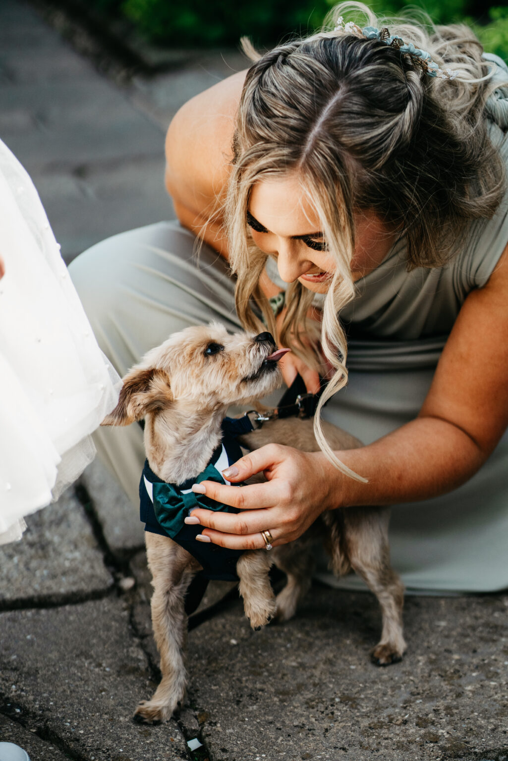 Woman crouching, petting dressed dog.