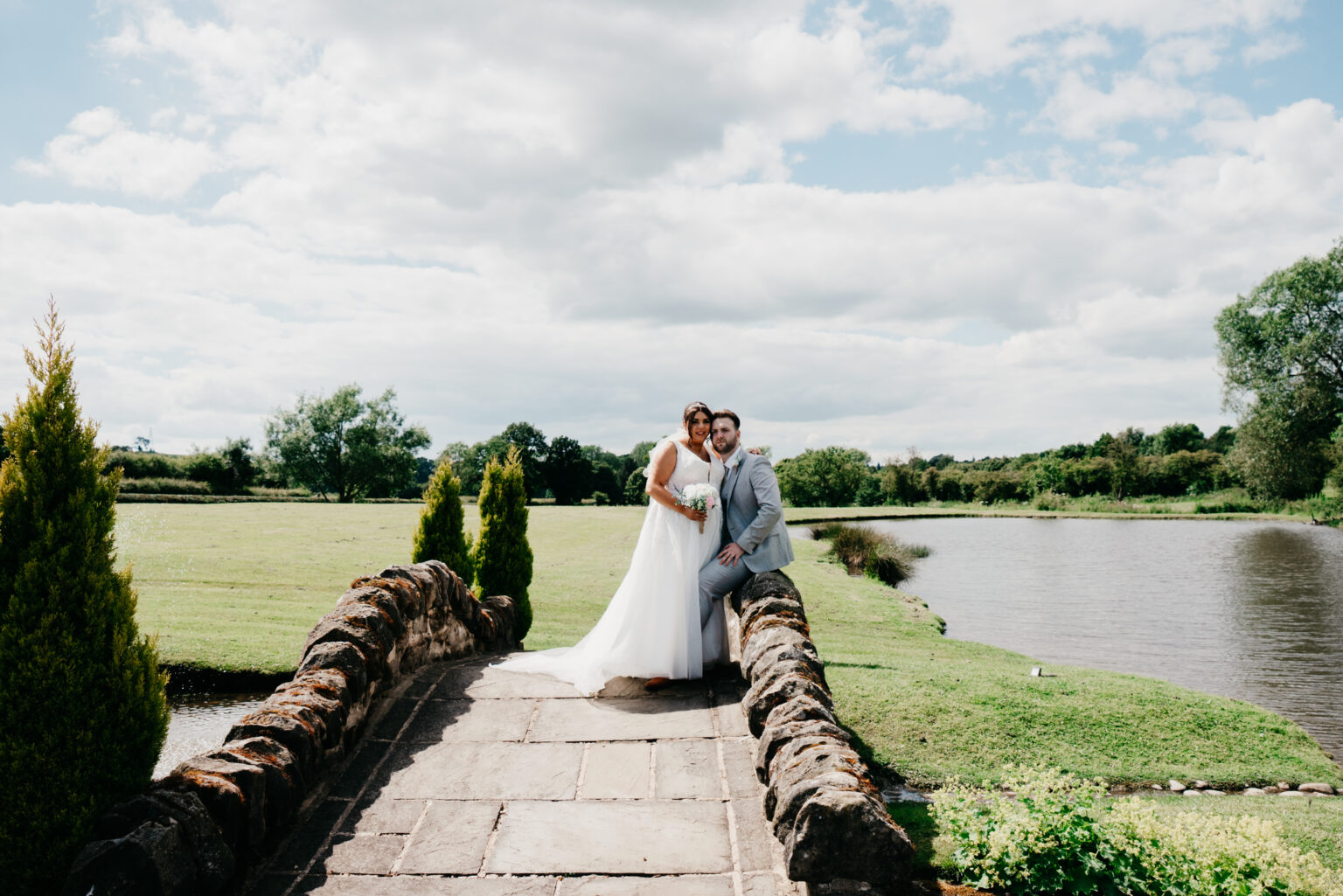 Bride and groom on stone bridge by lake