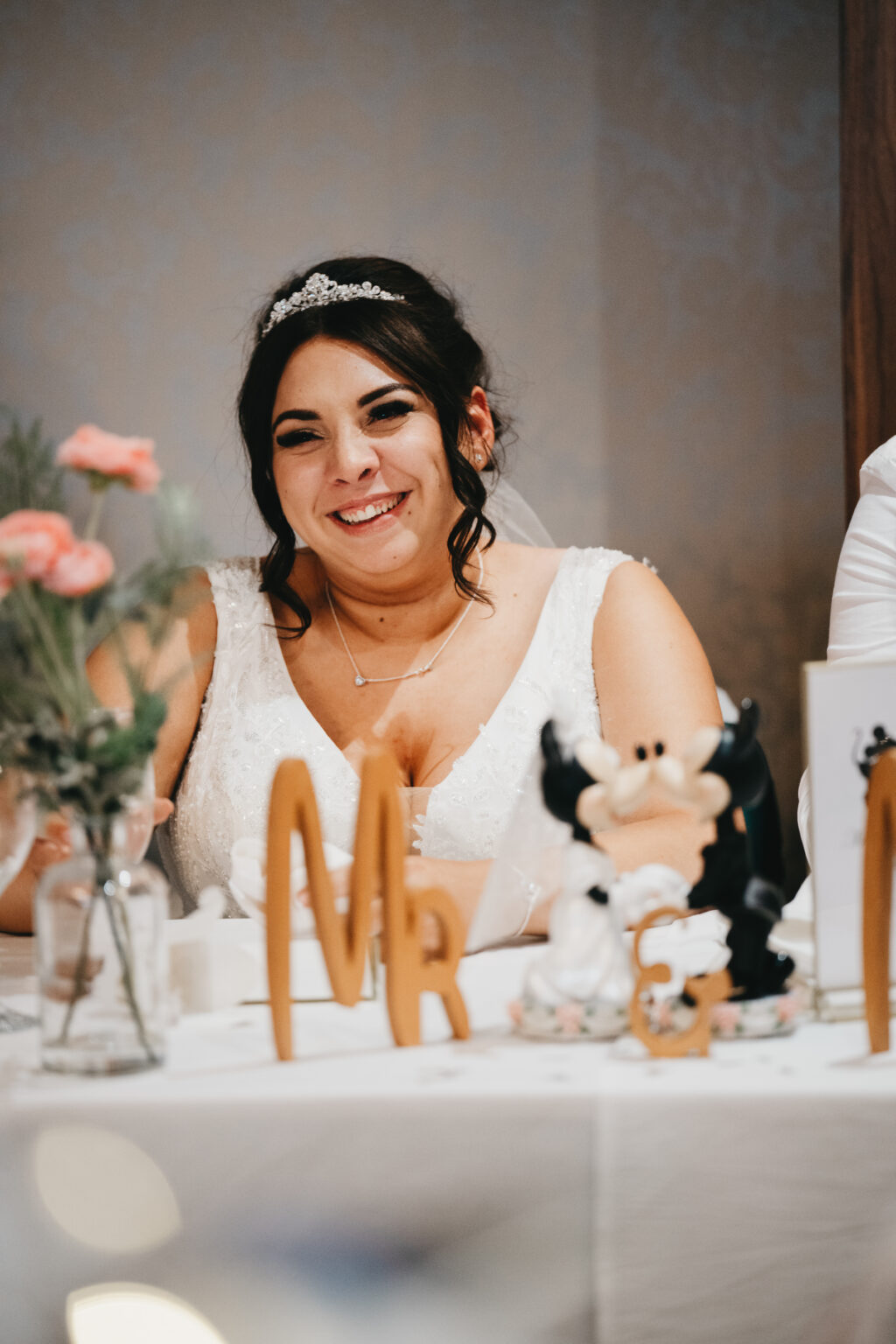 Smiling bride at a wedding reception table.