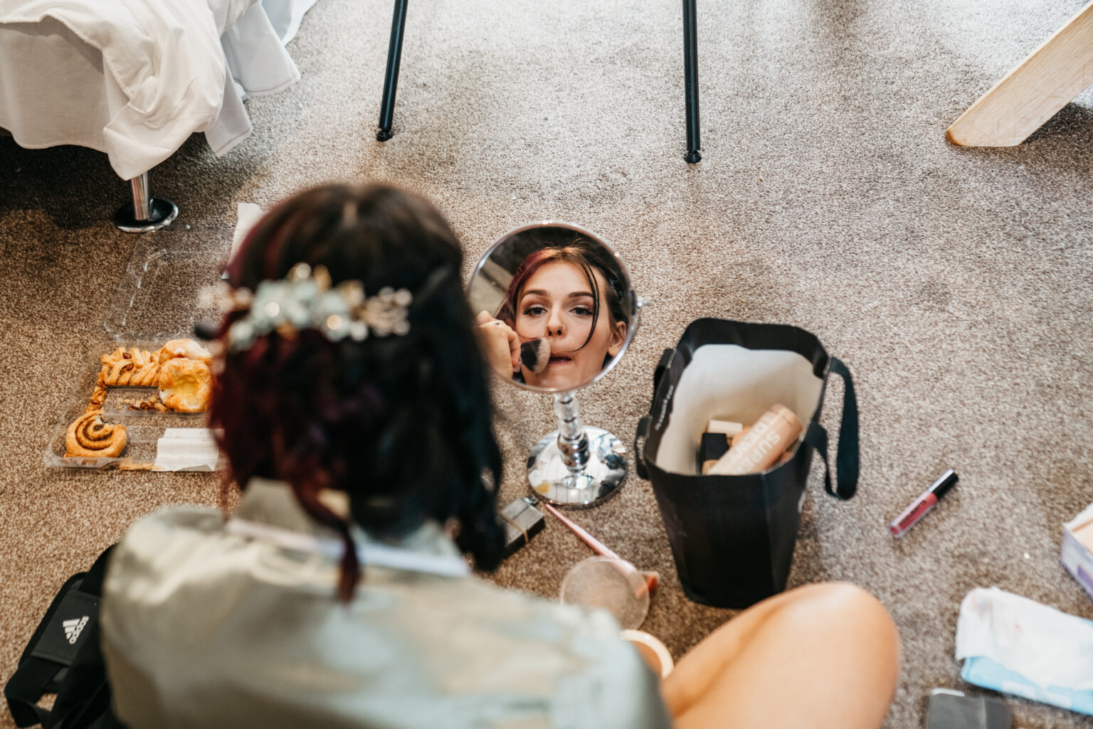Woman applying makeup, reflection in mirror.