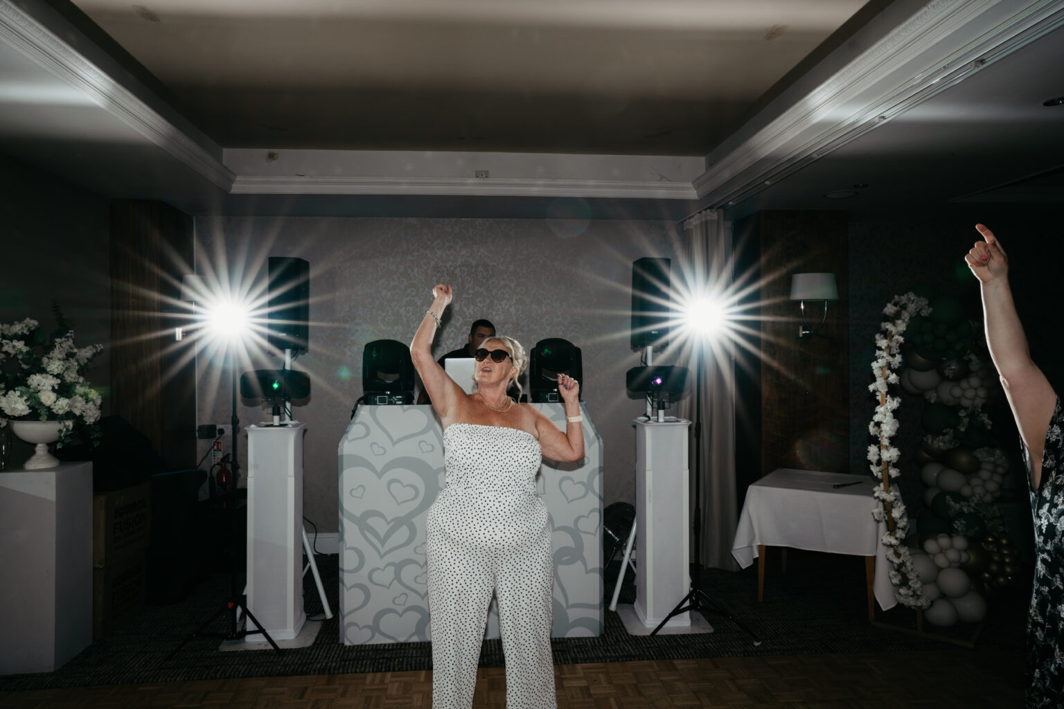 Woman dancing energetically at a party with DJ.