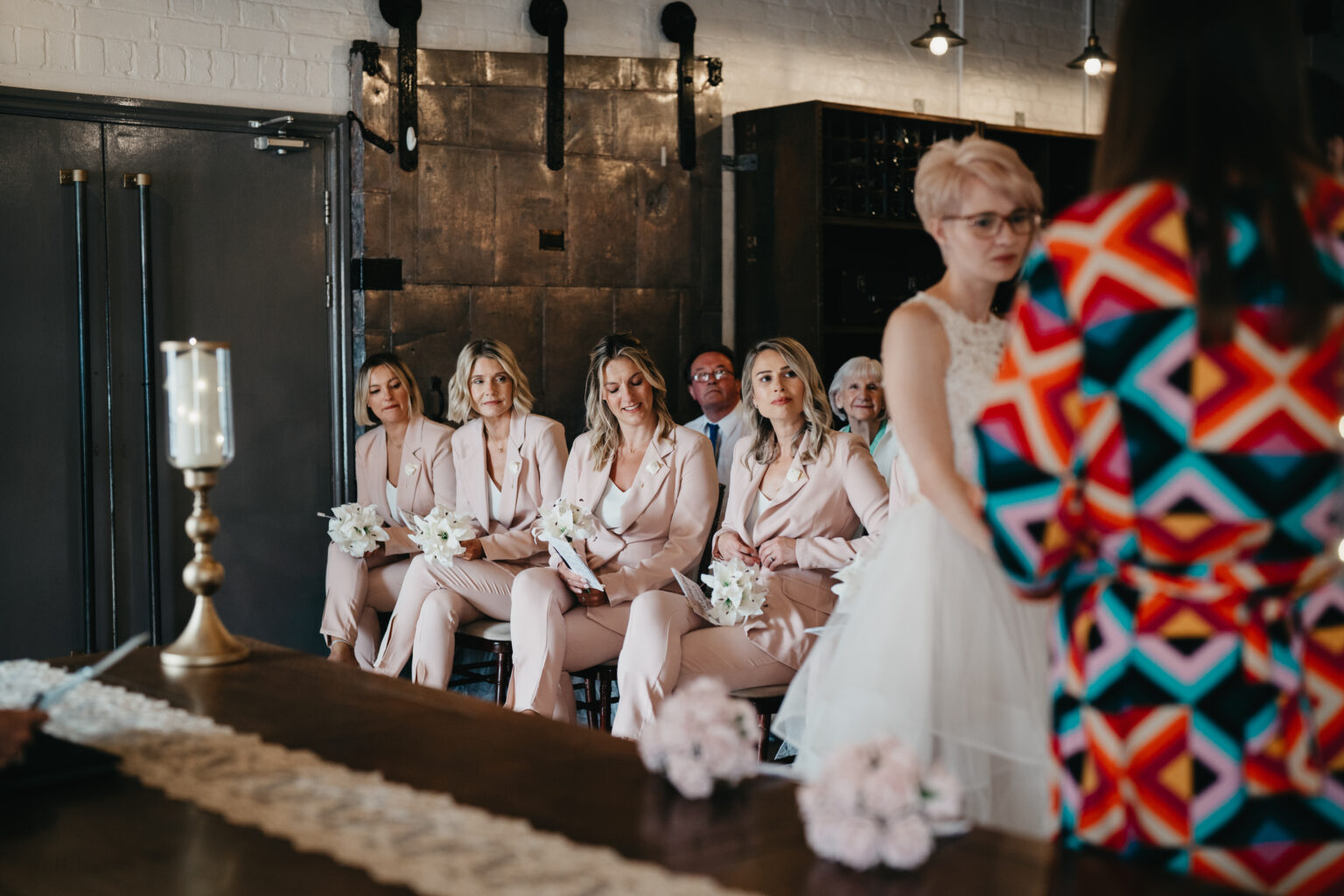 Bridesmaids in pink suits at wedding ceremony.