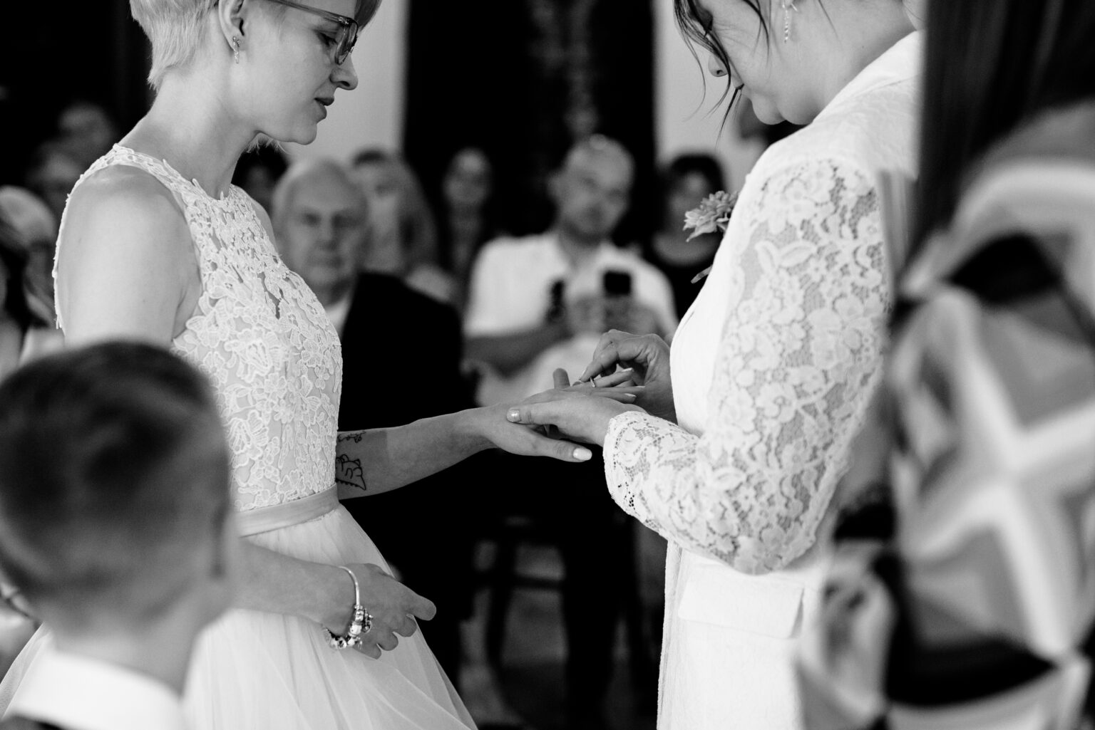Two women exchanging wedding rings, ceremony setting.