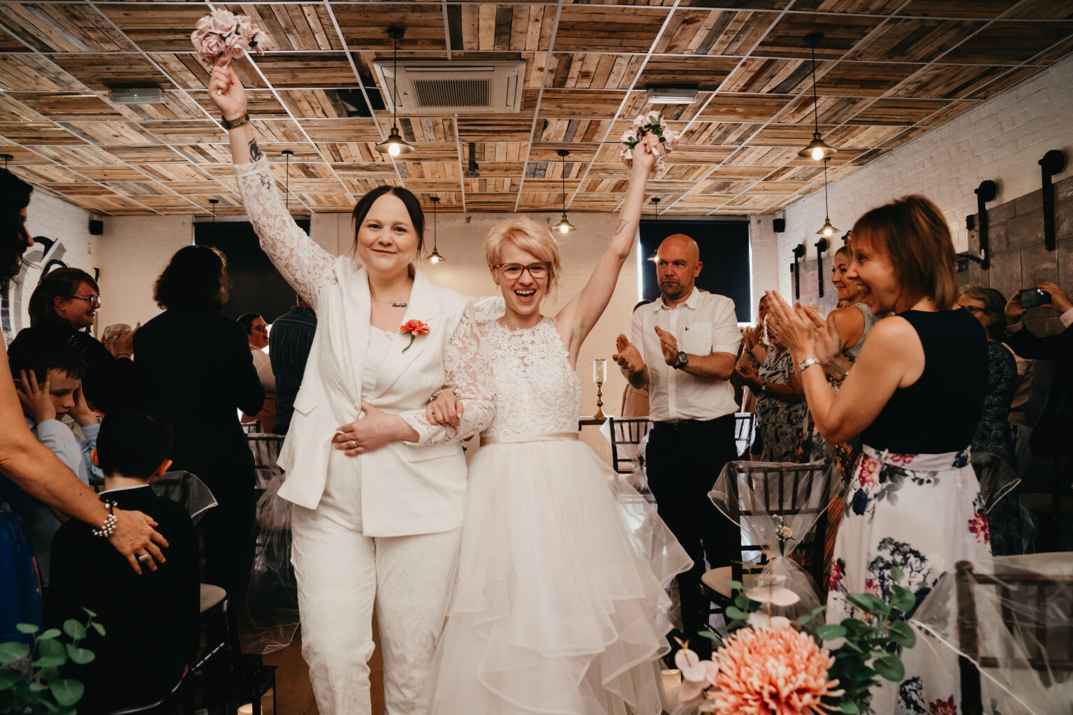 Happy couple celebrate wedding with guests applauding.