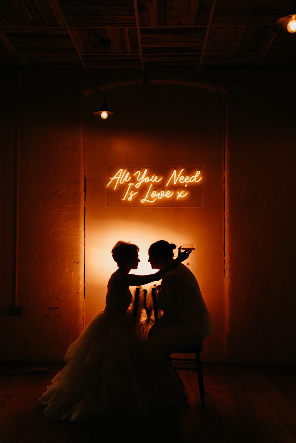 Couple silhouette under neon 'All You Need Is Love'
