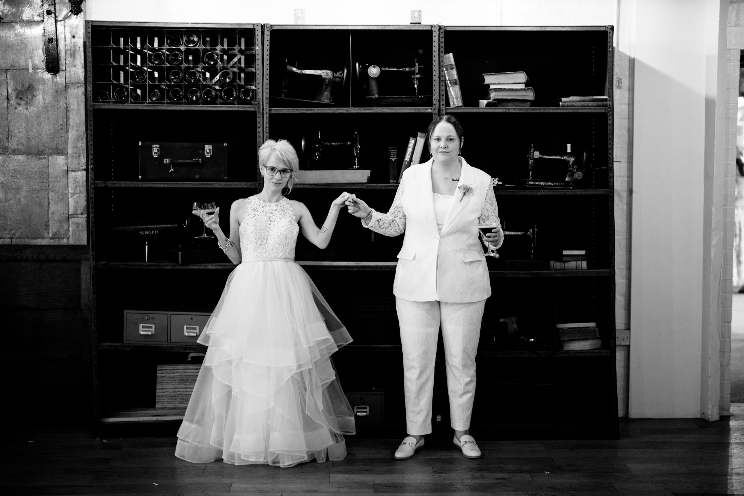 Couple holding hands in front of bookshelves.