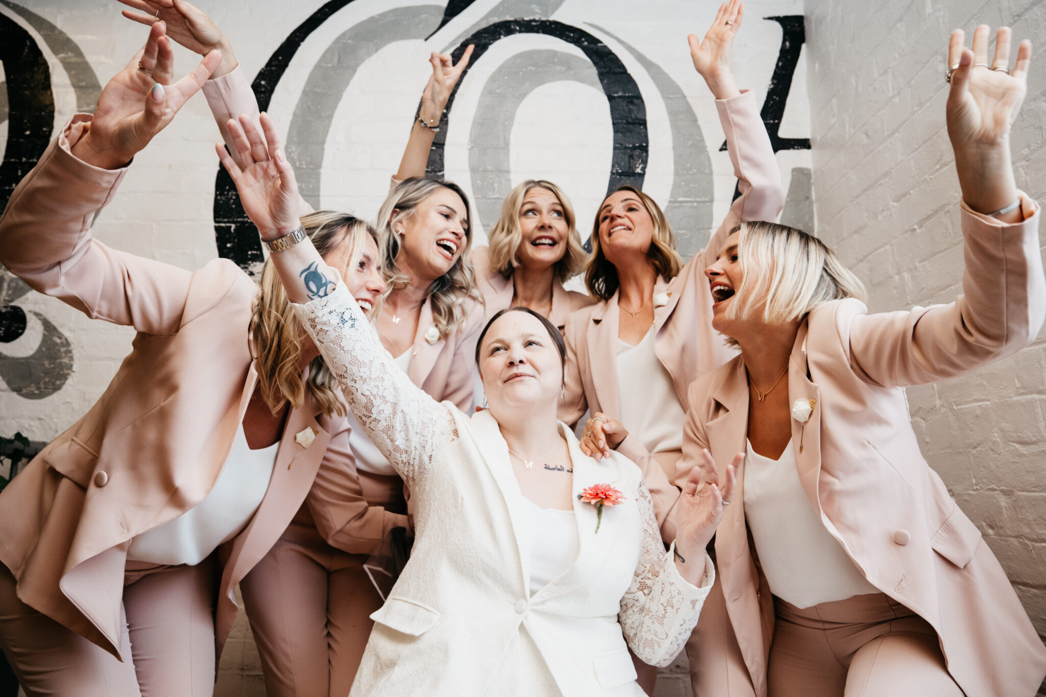 Laughing women in pink suits celebrating together.