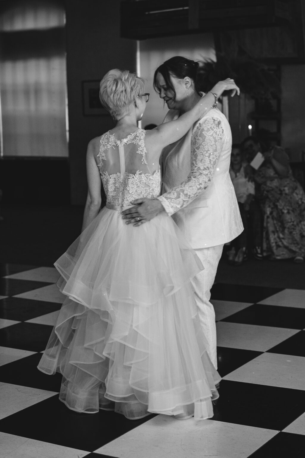 Couple dancing at wedding reception with guests watching.