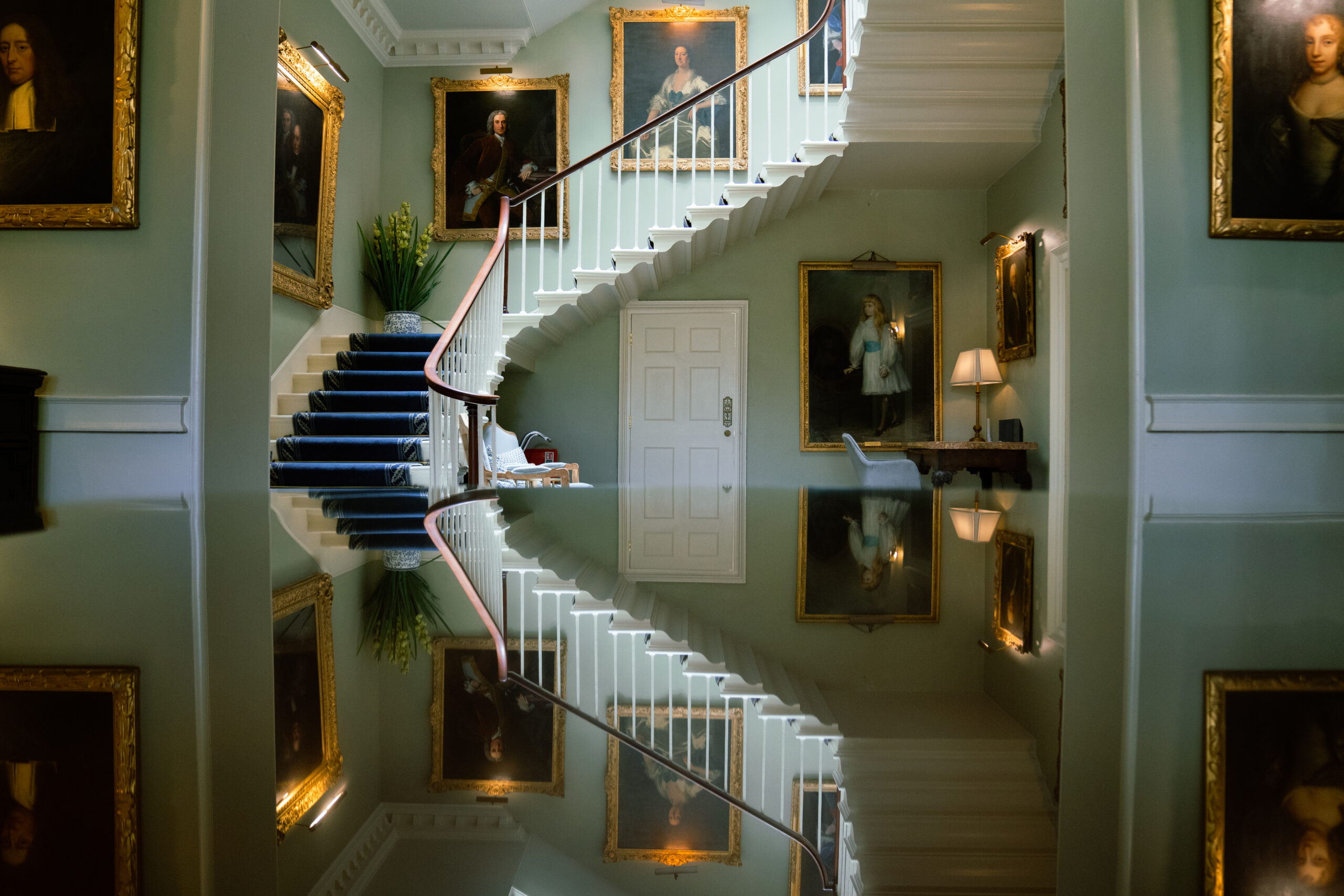Elegant staircase with framed portraits and reflection