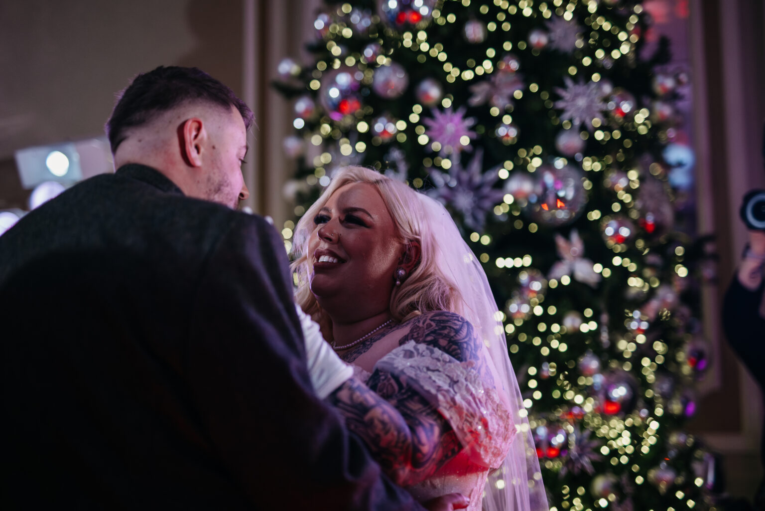 Bride and groom dancing by Christmas tree