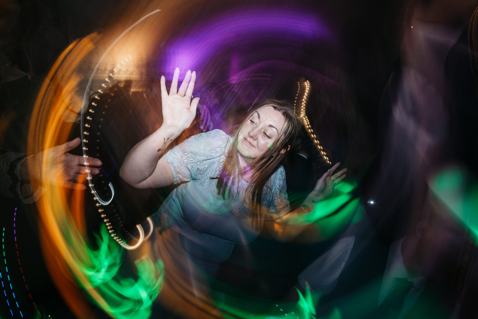 Woman dancing surrounded by colourful lights.