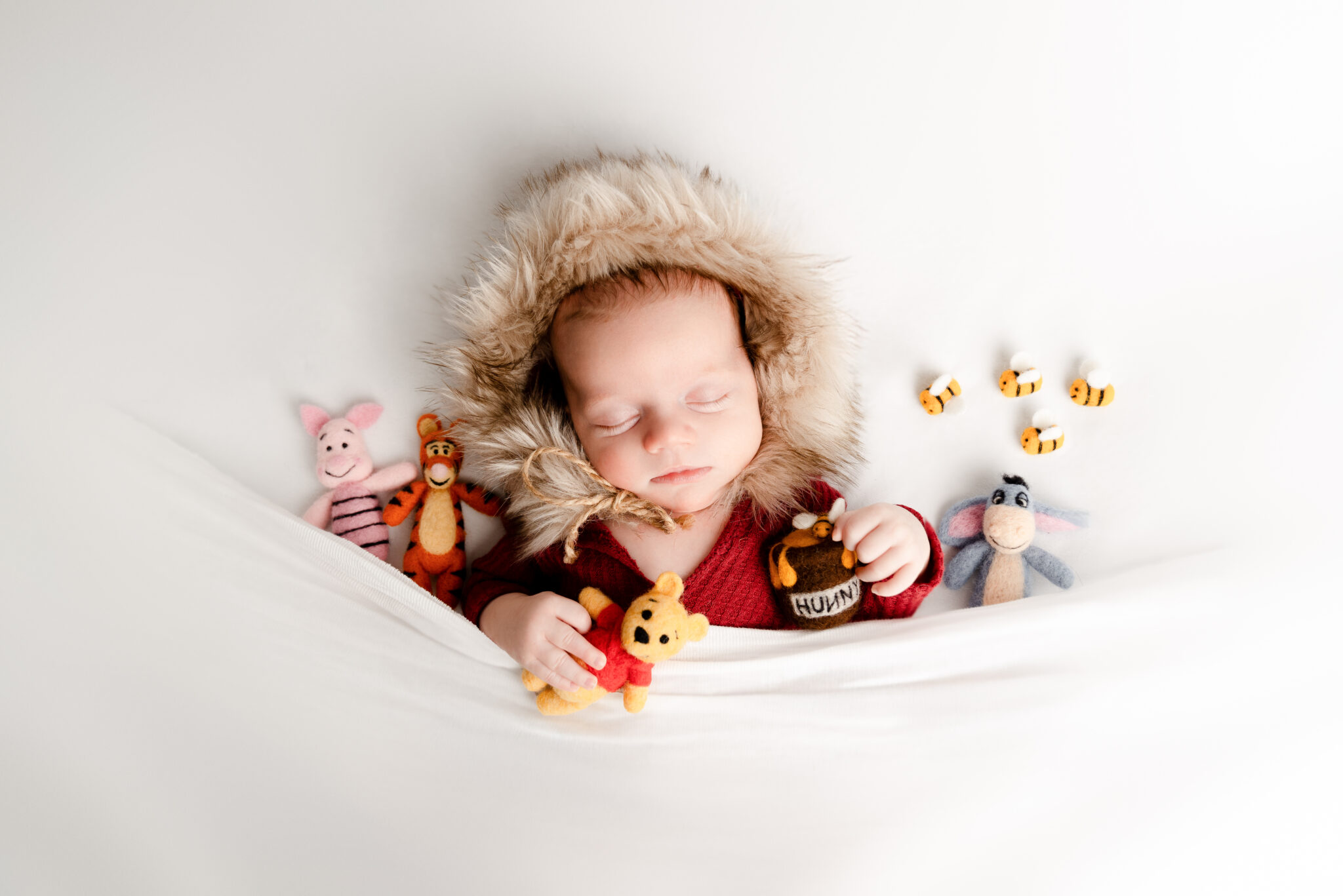 Baby sleeping with animal toys in fur hood.