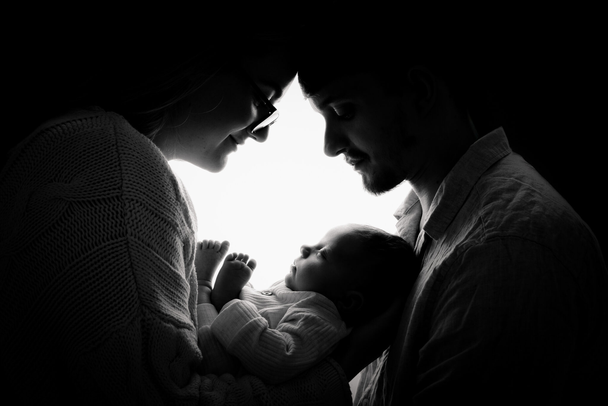 Silhouette of parents holding newborn baby.