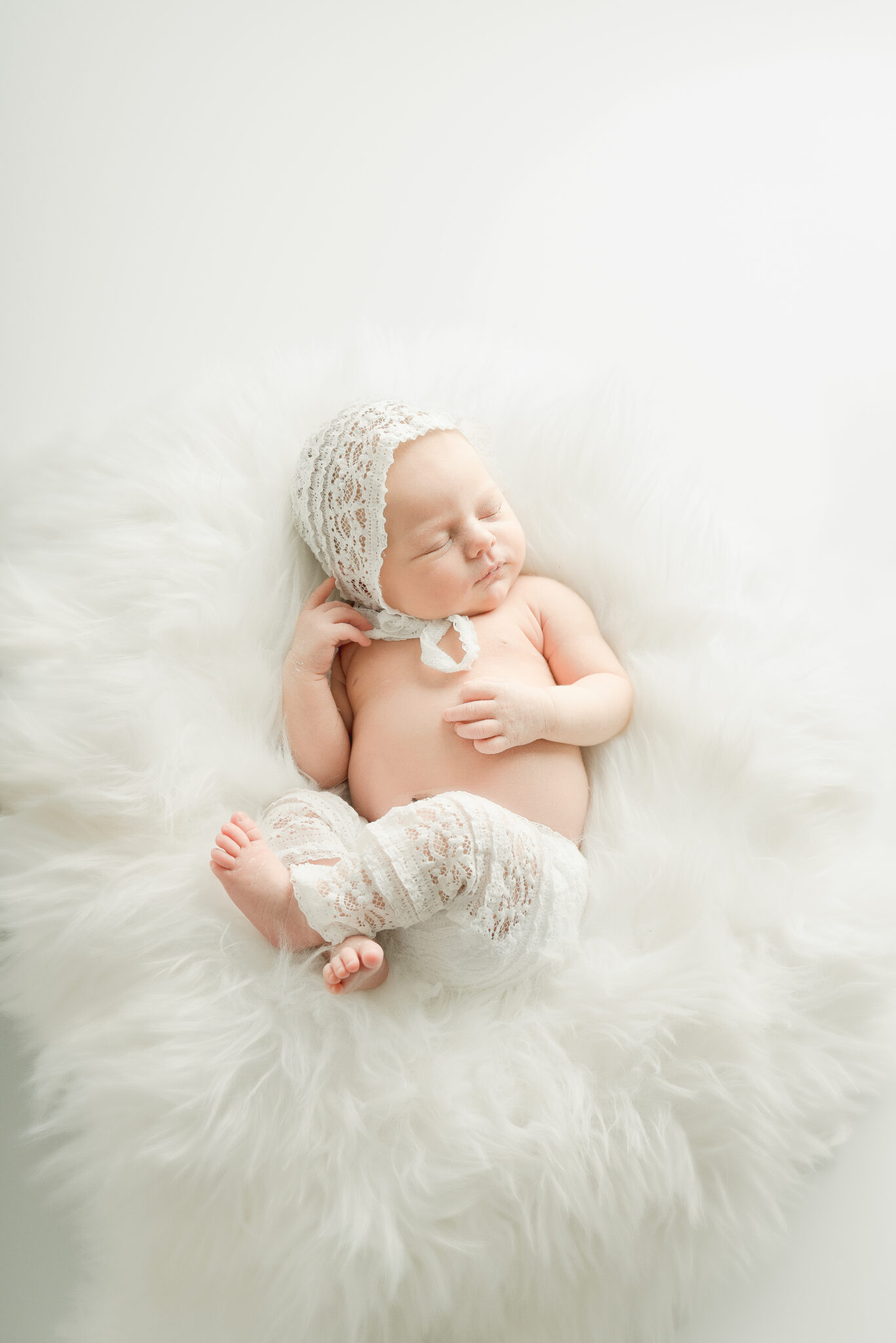 Sleeping baby in white lace outfit on blanket