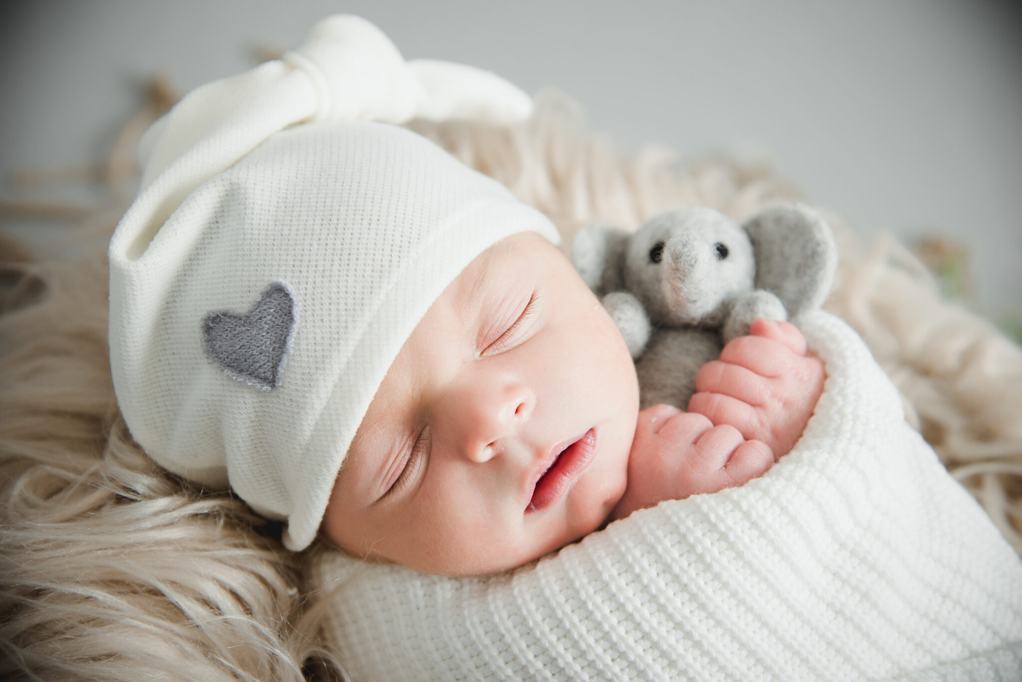 Sleeping baby with toy elephant, cosy blanket