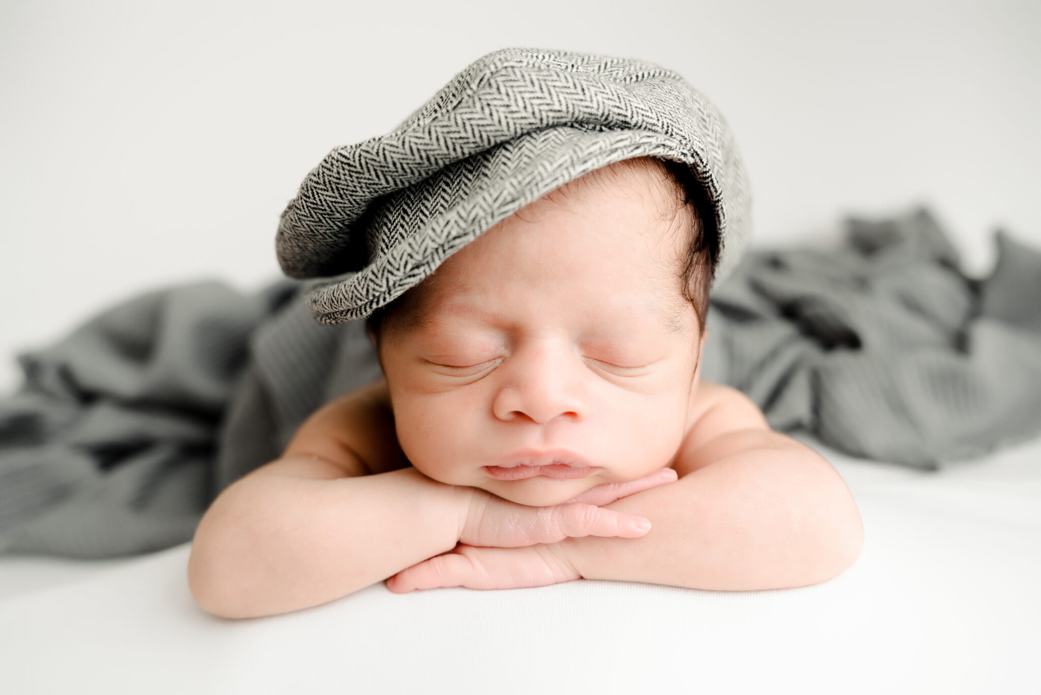 Sleeping baby with grey cap and blanket.