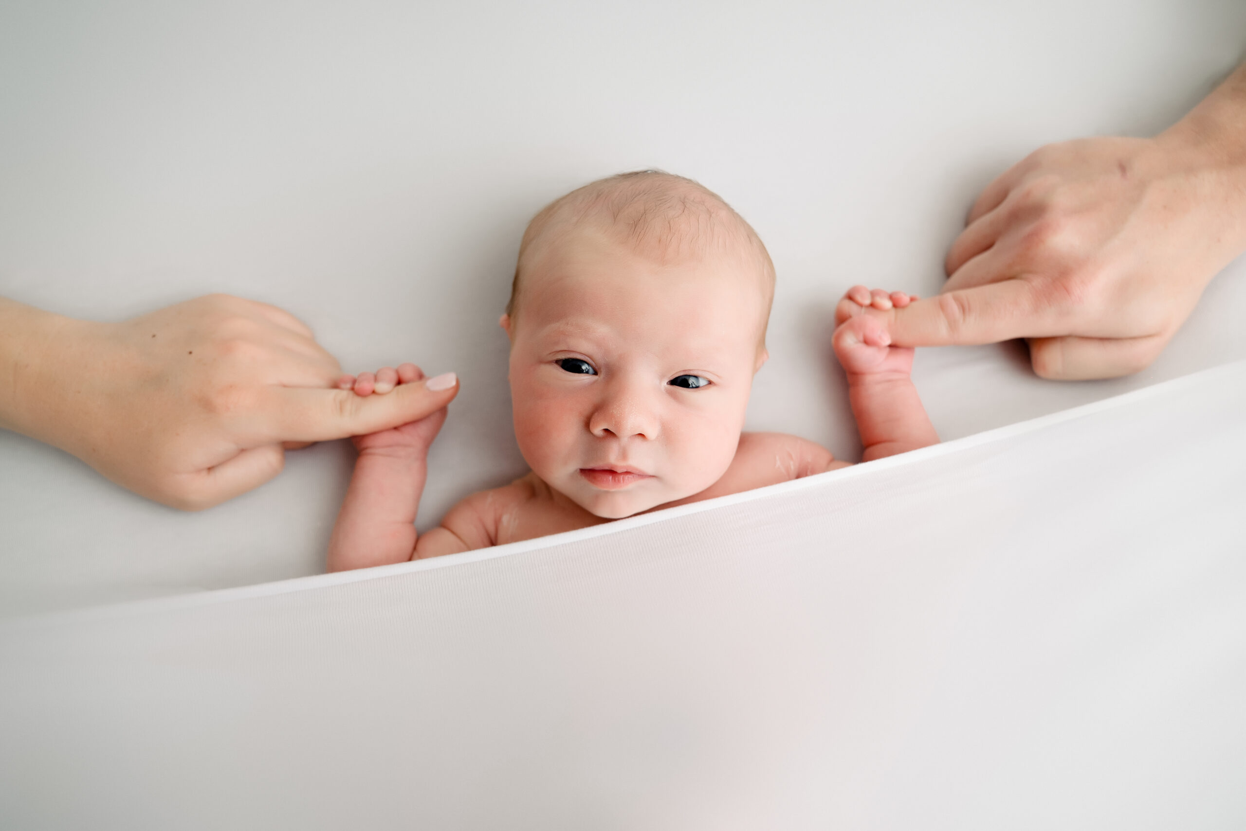 Newborn baby holding parents' fingers