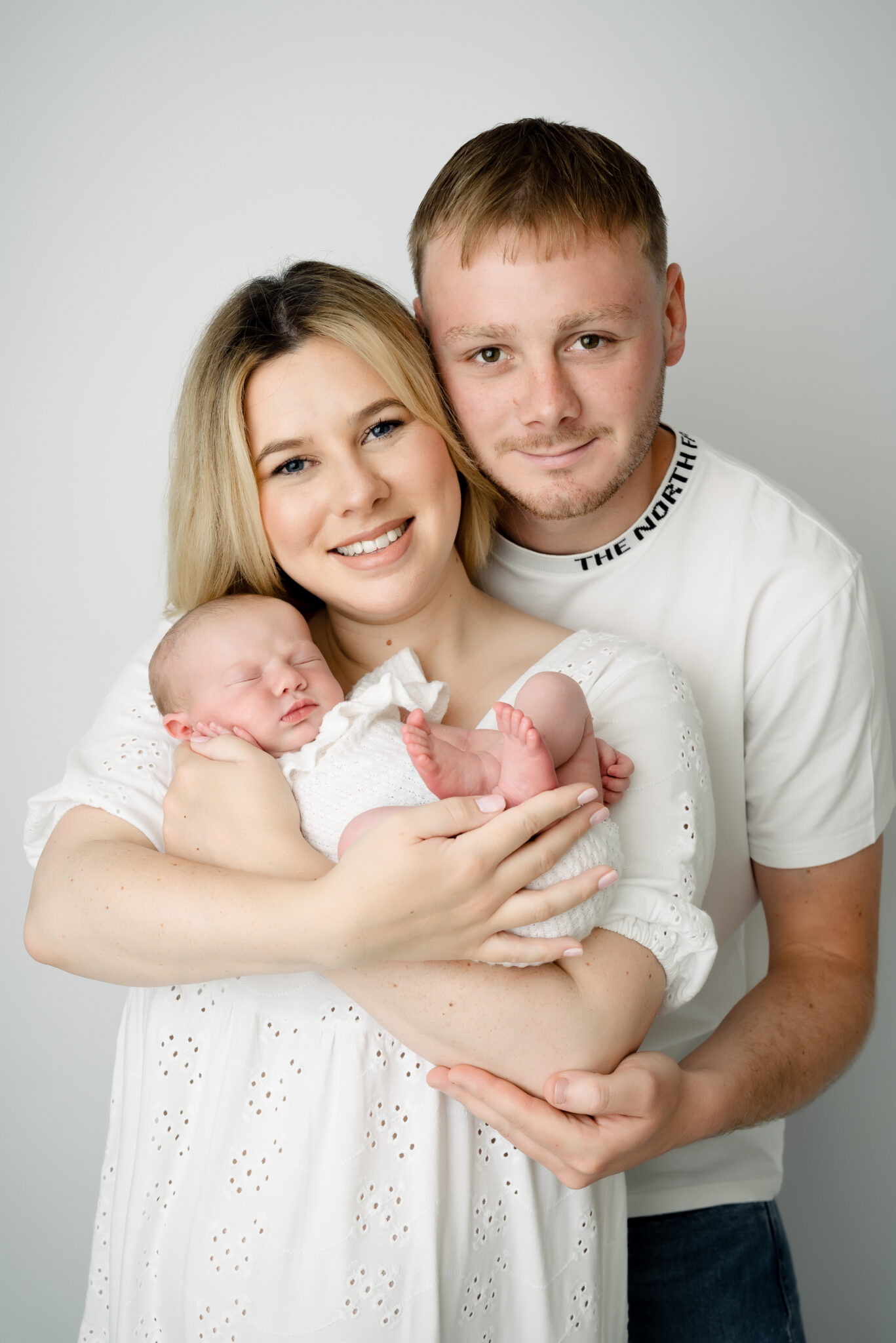 Happy family with newborn baby, white background.
