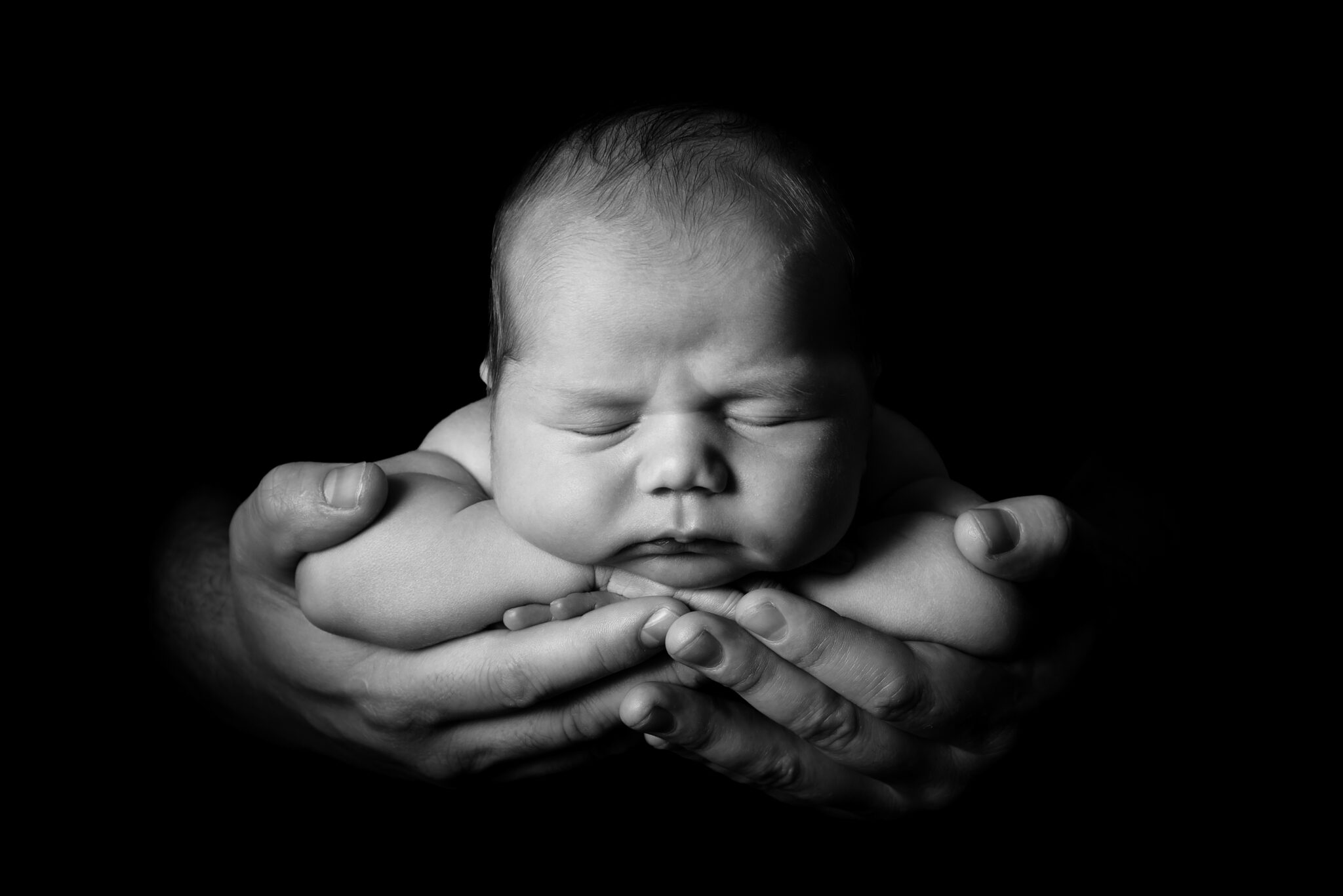 Black and white photo of baby in hands.