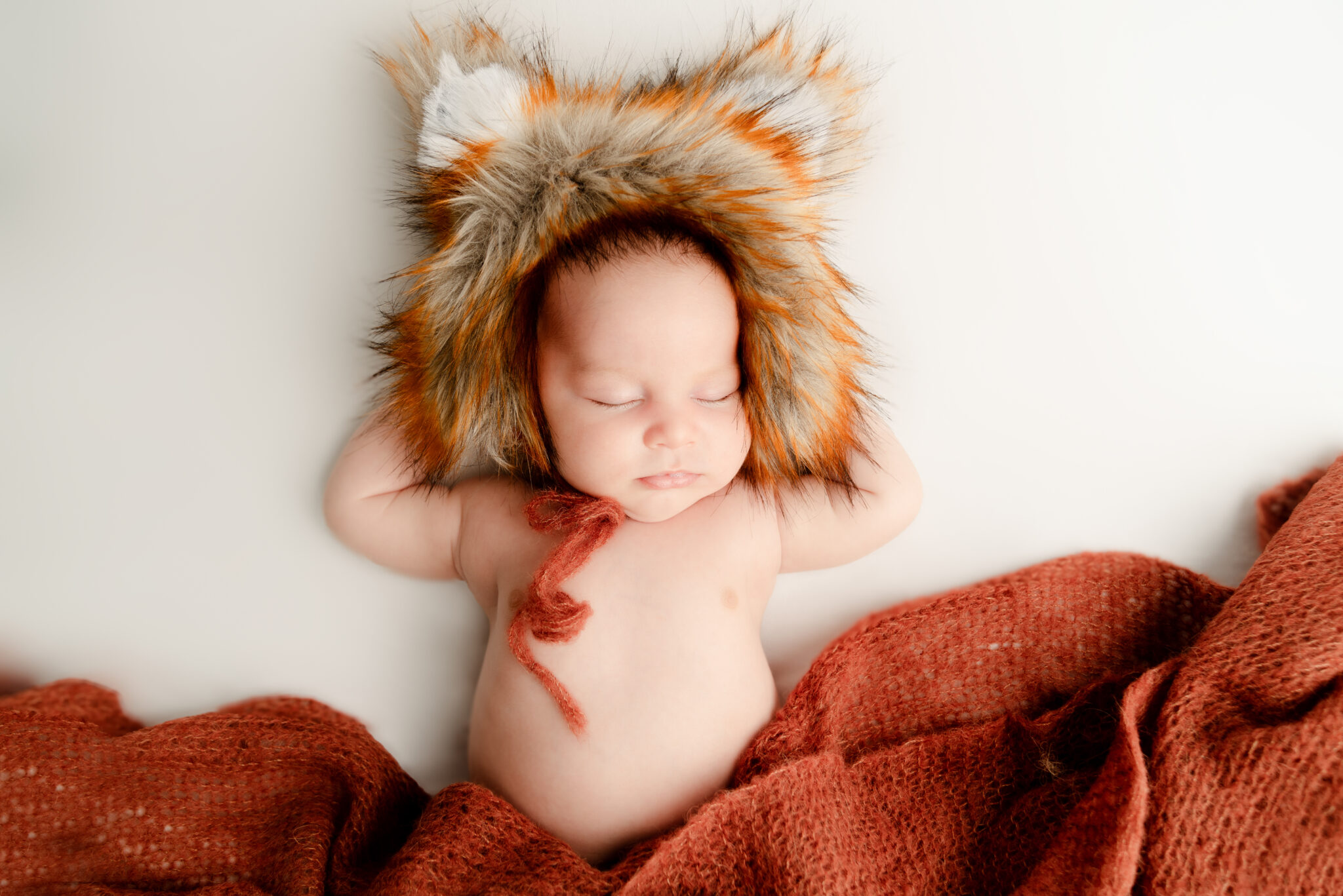 Sleeping baby with furry hat and blanket.