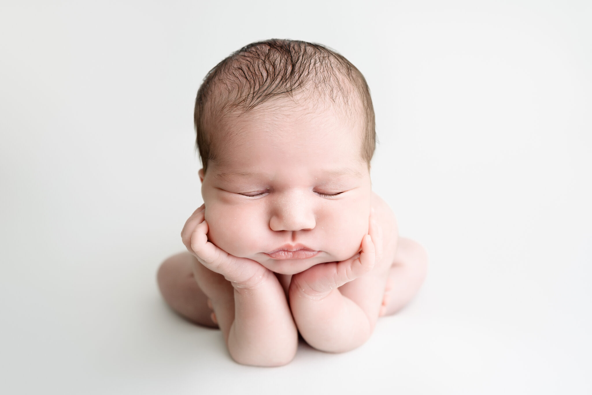 Sleeping newborn baby with hands on cheeks