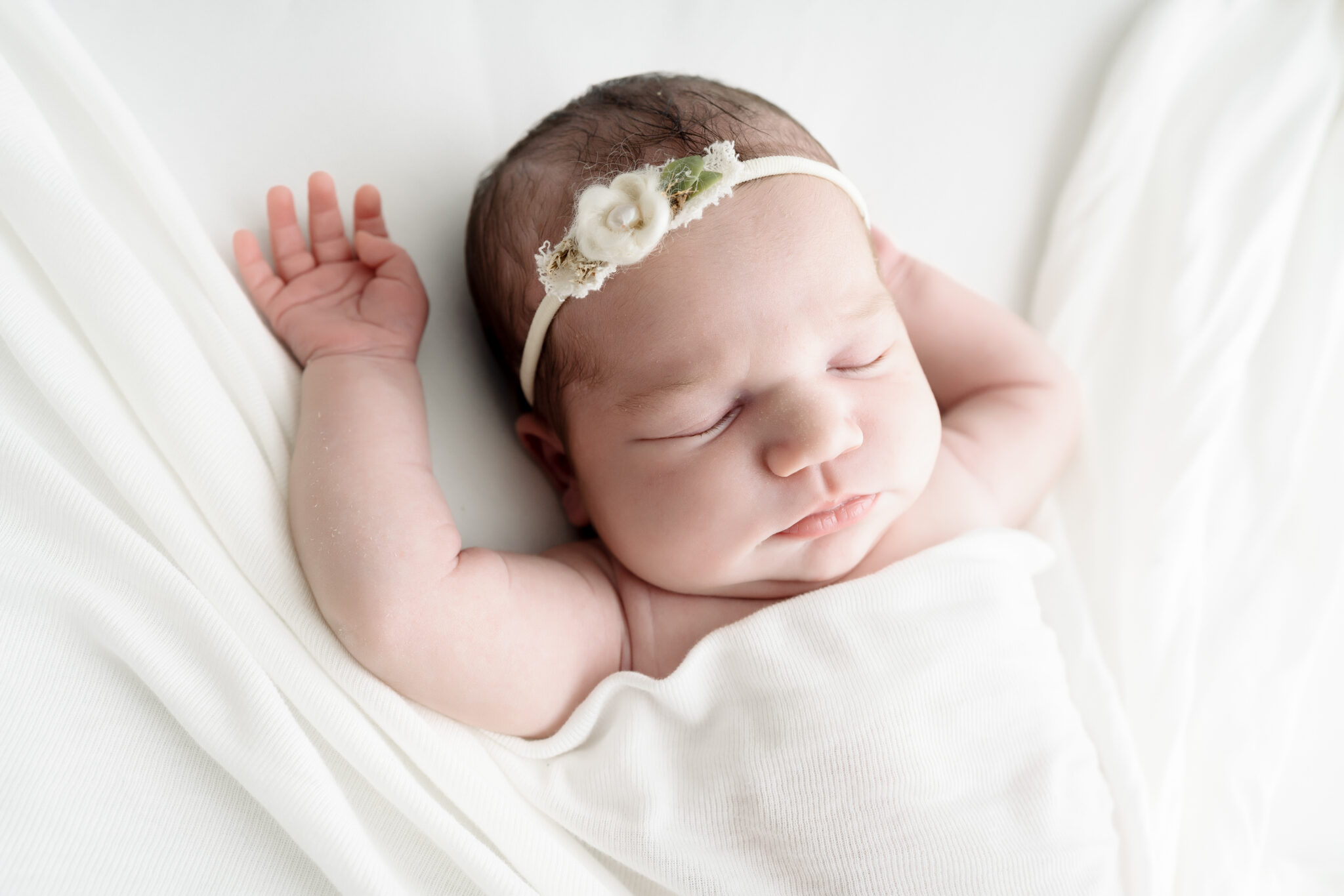 Newborn baby sleeping in white blanket.