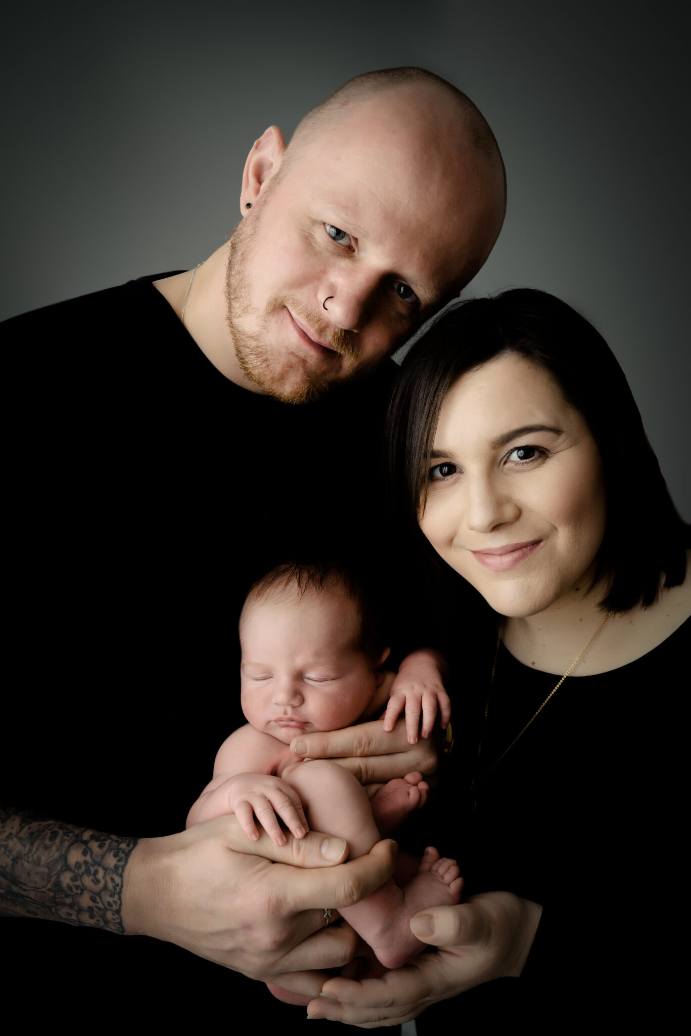 Couple holding newborn baby together, smiling.