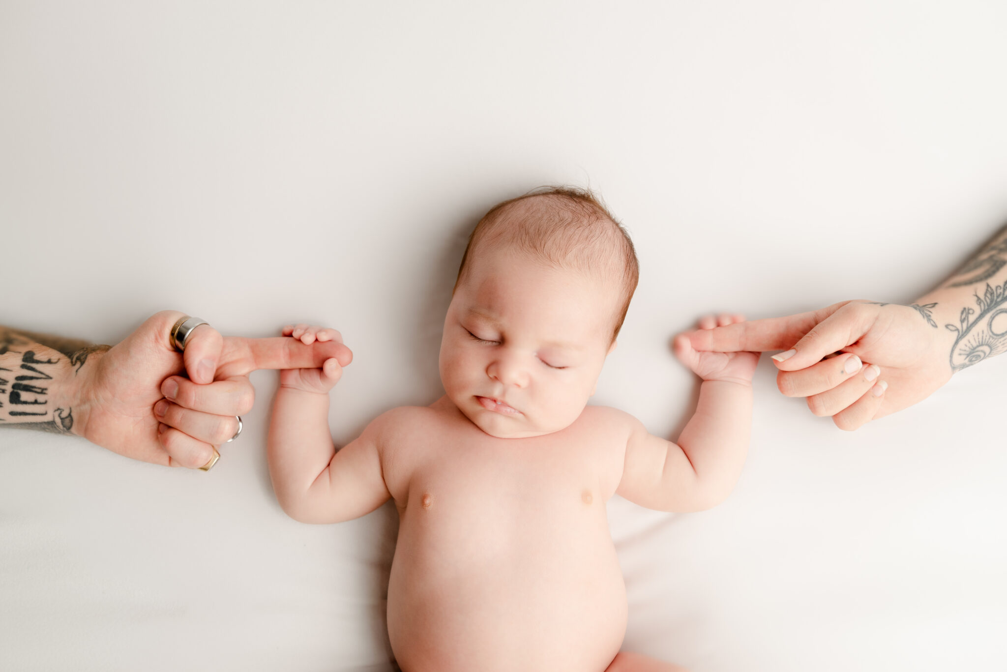 Baby holding parents' fingers while sleeping