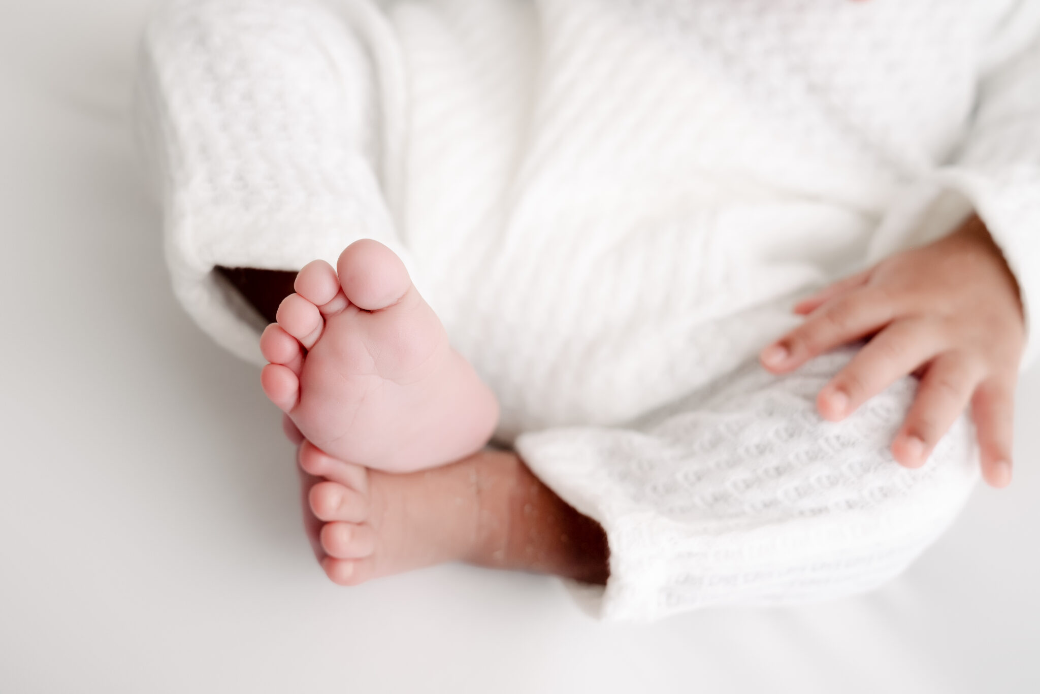 Close-up of baby feet in white clothing.