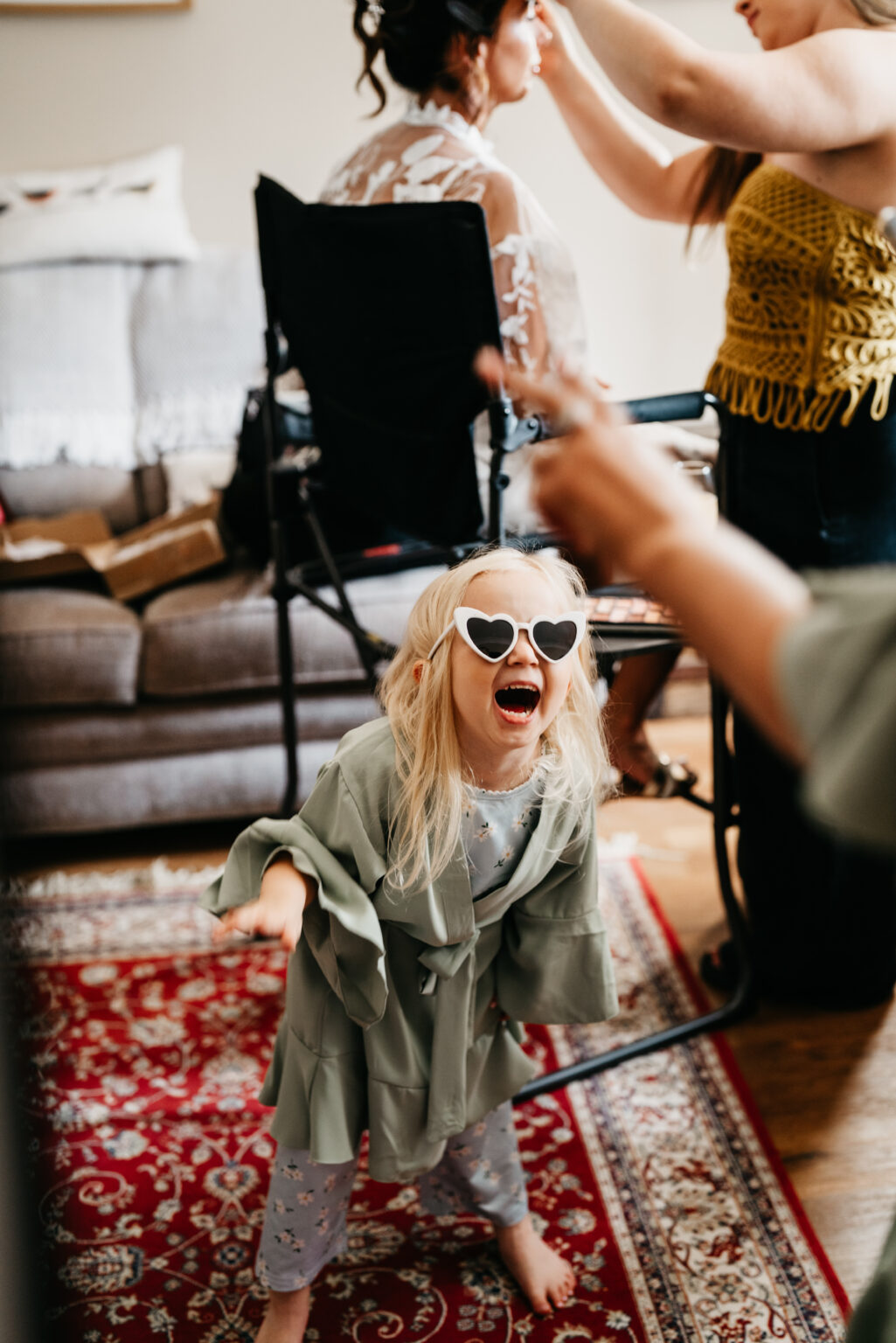 Laughing child wearing heart-shaped sunglasses indoors.