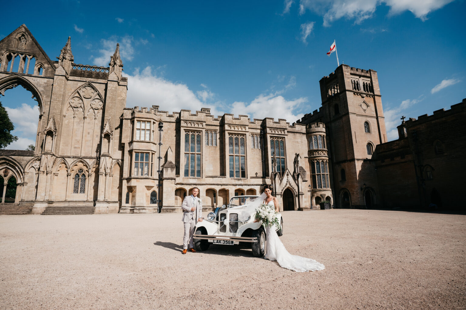 Bride and groom by vintage car outside castle