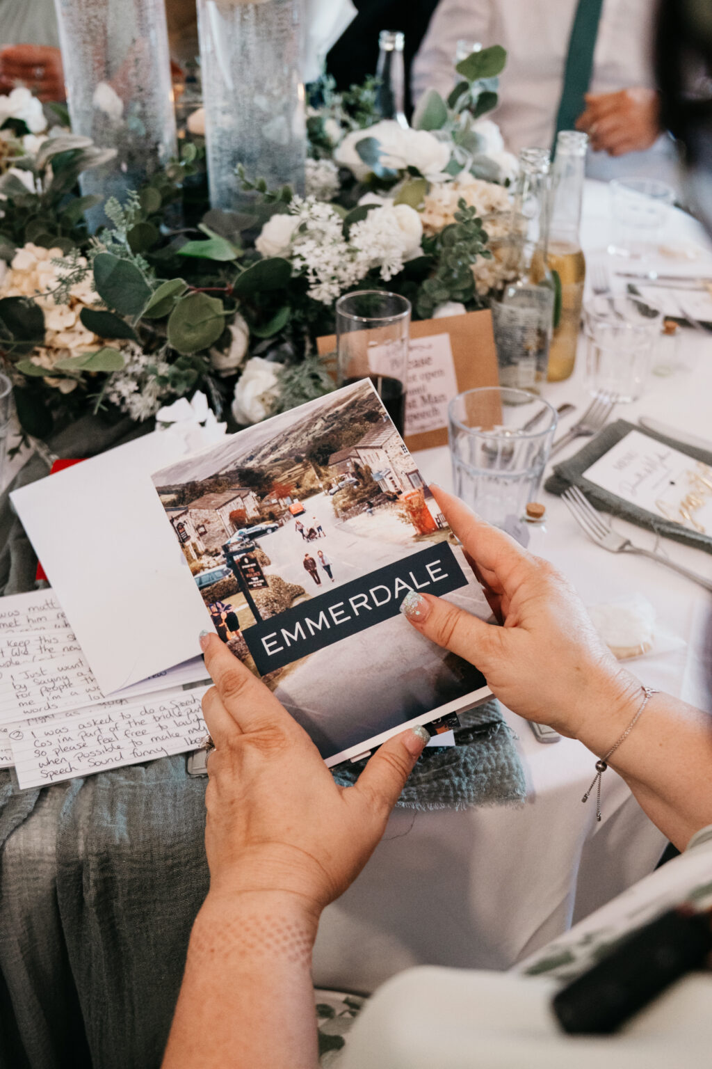 Person holds Emmerdale-themed booklet at decorated table.