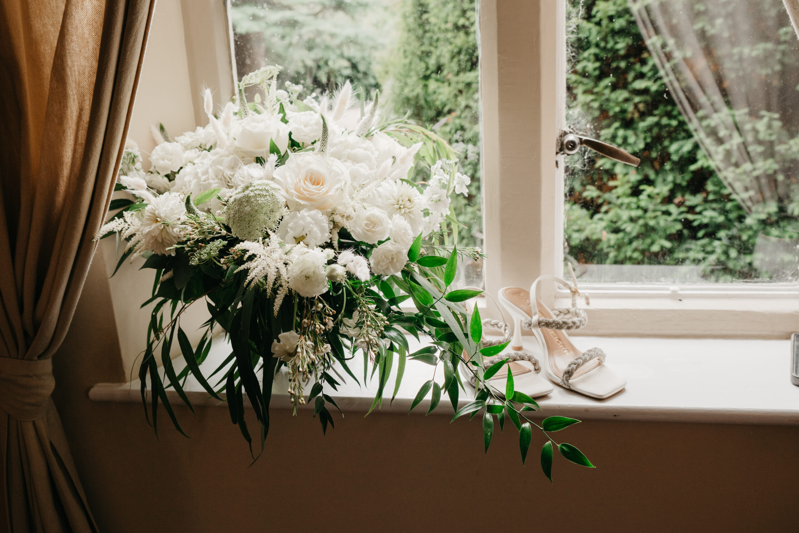 White floral bouquet beside window with sandals