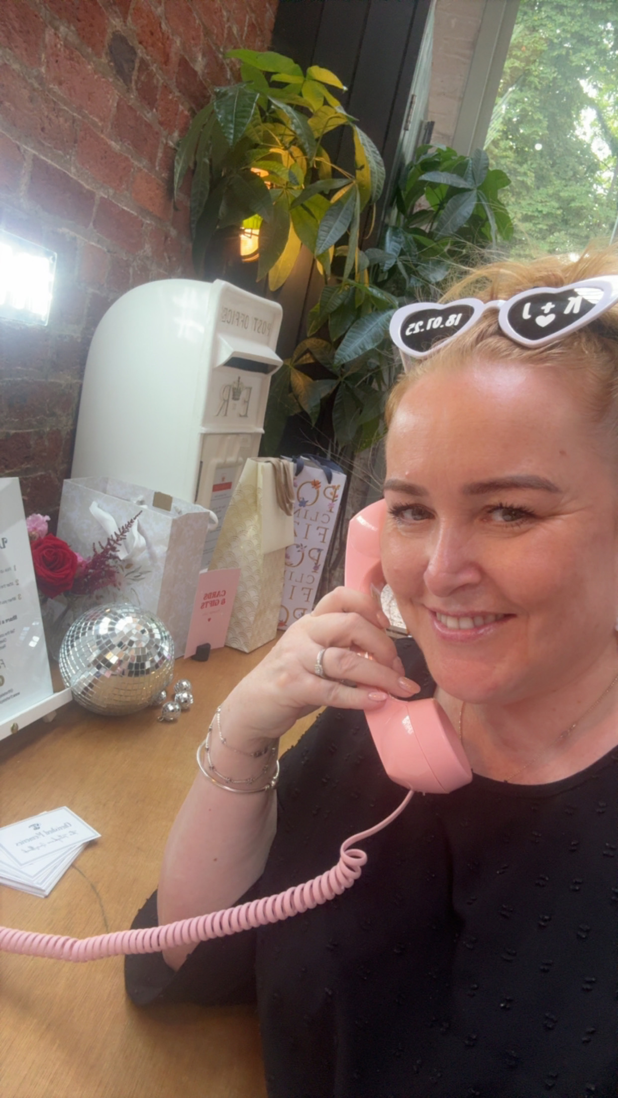 Woman smiling while using a pink telephone.
