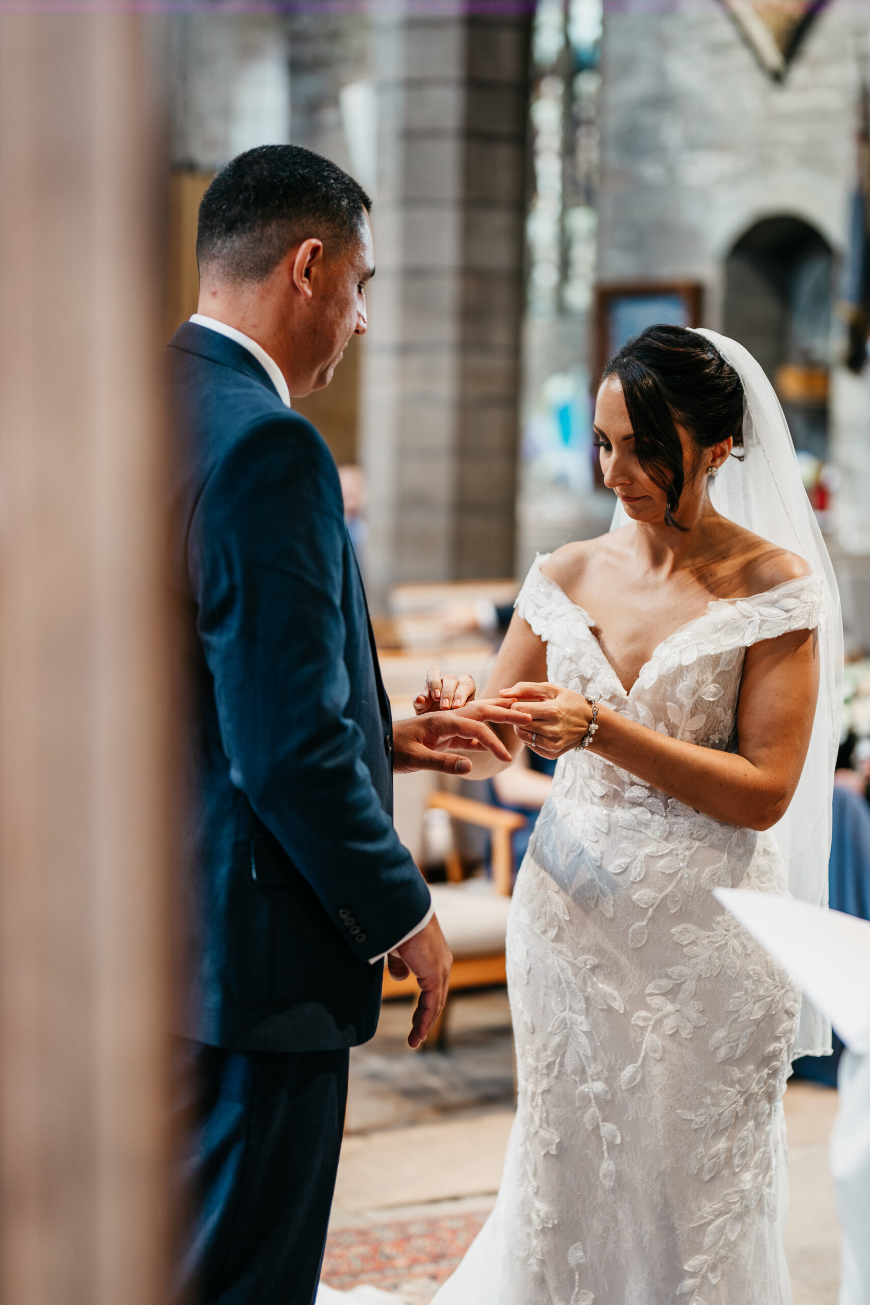 Bride placing ring on groom at wedding ceremony.