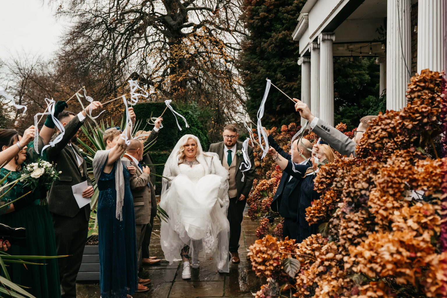 Bride and groom exit wedding with smiling guests.